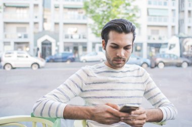 Açık havada akıllı telefon kullanan genç adam.
