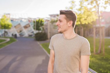 Açık havada tasasız genç, beyaz, dingin bir adamın portresi. 