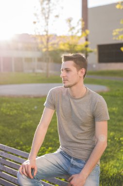 Açık havada tasasız genç, beyaz, dingin bir adamın portresi. 