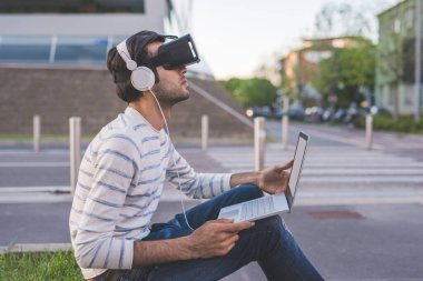 Genç Hintli adam dışarıda bilgisayar oyunu ve 3 boyutlu izleme kullanıyor.