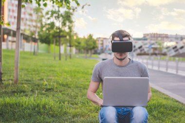 Genç beyaz adam dışarıda 3 boyutlu izleme ve bilgisayar oyunu kullanıyor.