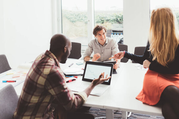 Three millennials multiethnic business people having meeting indoors using computer discussing