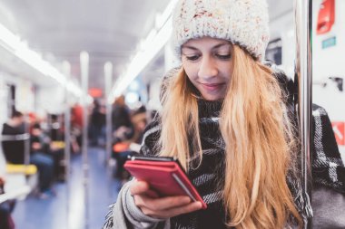 Genç, güzel, kakuasyalı sarışın kadın akıllı telefon kullanarak yeraltında seyahat ediyor. Video oyunu, ekoomerce, video konsepti.
