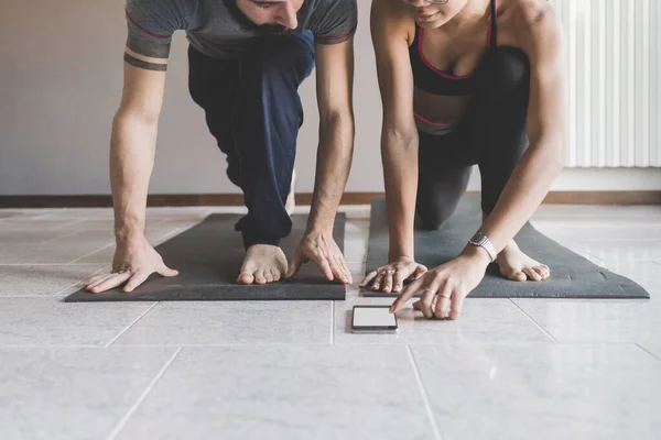Pasangan Multietnis Rumah Berlatih Olahraga Melakukan Yoga Kebugaran Menggunakan Smartphone — Stok Foto