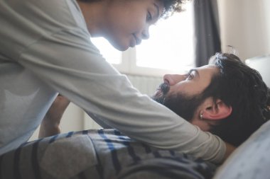 Genç, etnik çeşitlilikte çift yatak odasında kucaklaşıyor.