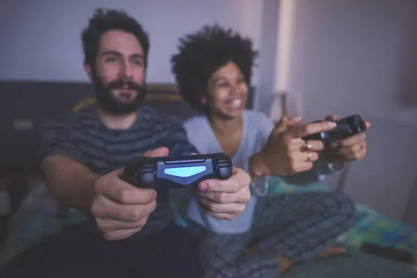 年轻的多族裔夫妇卧室玩电子游戏 — 图库照片