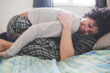 Genç, etnik çeşitlilikte çift yatak odasında kucaklaşıyor. 