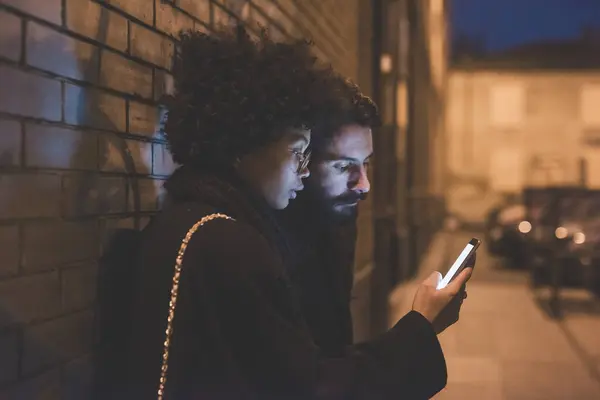 Junges Multiethnisches Paar Umarmt Sich Nachts Mit Smartphone Freien — Stockfoto