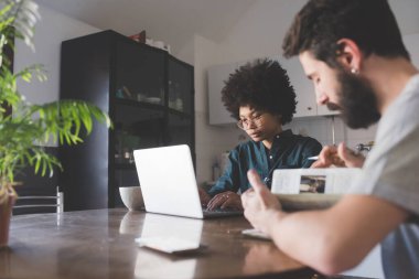 Evde bilgisayar ve gündem kullanarak çalışan çok ırklı genç bir çift. 