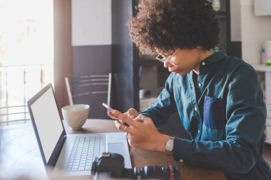 Evde bilgisayar ve akıllı telefon kumandası kullanan çok ırklı genç bir kadın var. 