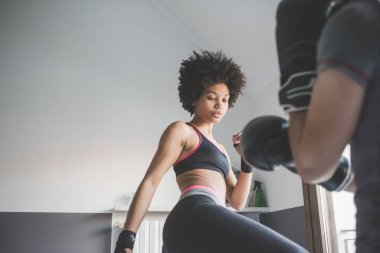 Evde antrenman yapan çok ırklı genç bir kadın, boks antrenmanı yapıyor.