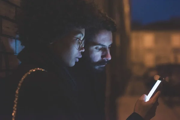 Pasangan Multietnis Muda Berpelukan Menggunakan Smartphone Toghether Outdoor Malam Hari — Stok Foto