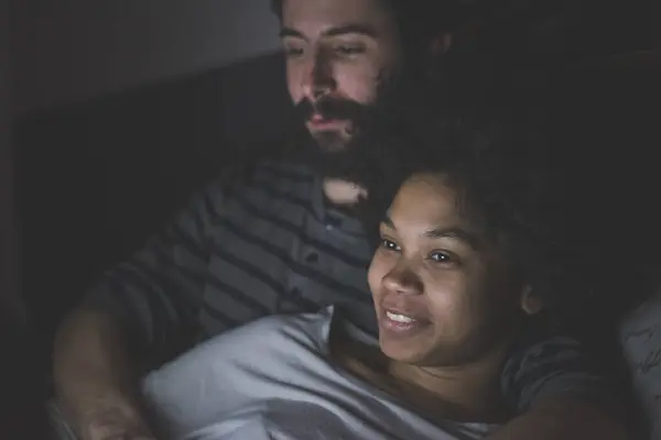 Pasangan Muda Multietnis Dalam Ruangan Menggunakan Komputer Berbaring Tidur Malam — Stok Foto