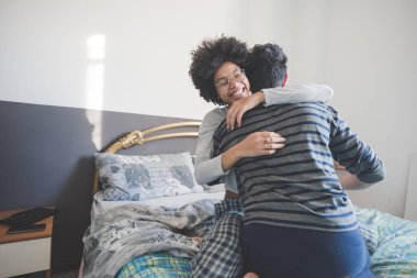 Genç çok ırklı insanlar yatak odasında gülüp eğleniyorlar. 