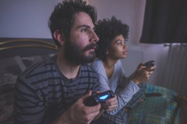 Genç çok ırklı çift yatak odası video oyunu oynuyor  