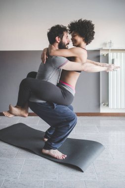Evde spor yapan, yoga yapan çok ırklı bir çift var.   