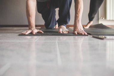 Düşük seviyeli çok ırklı çift evde spor yaparken yoga yapıyor.   