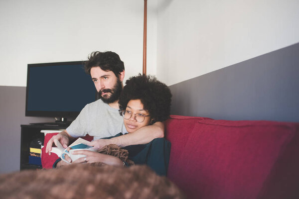 Young Multiethnic Couple Relaxing Lying Couch Blanket Reading Book Having Royalty Free Stock Photos