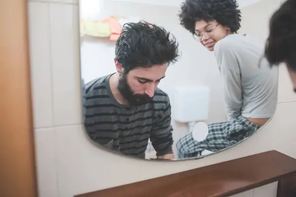 若い多民族ミレニアル世代カップルは トイレで朝のルーチンを過ごしています ロイヤリティフリーのストック写真