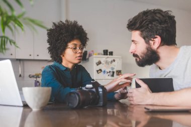 Evde bilgisayar kullanarak çalışan çok ırklı genç bir çift.  