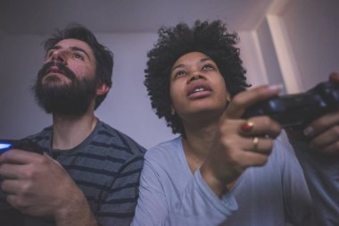 Genç çok ırklı çift yatak odası video oyunu oynuyor  