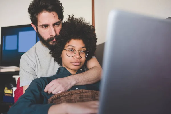 Young Multiethnic Couple Indoor Using Computer Sitting Couch Royalty Free Stock Images