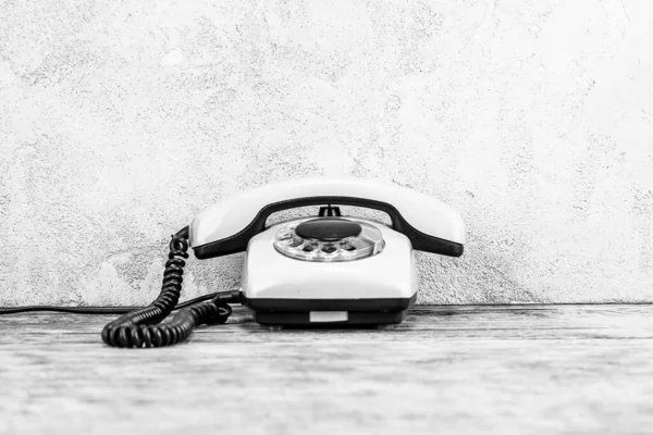 老式的白色转盘电话在木制桌子上 前面是灰色混凝土背景 黑白照片 — 图库照片