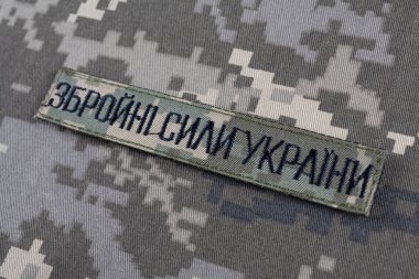 KYIV, UKRAINE - October 5, 2022. Russian invasion in Ukraine 2022. Ukraine Army uniform insignia badge on camouflaged uniform background. Text in ukrainian - Armed Forces of Ukraine clipart