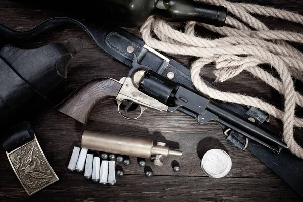Old West. Percussion Army Revolver with paper cartridges, bullets, powder flask and holster on wooden table