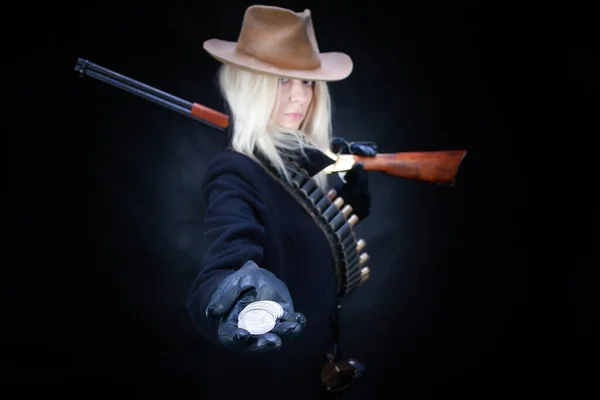 Old west blonde girl with silver dollars in hand and gun on black background
