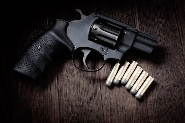 stock image revolver handgun with cartridges on wooden table