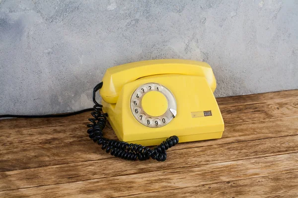 Vintage Żółty Telefon Obrotowy Drewnianym Stole Przednim Szarym Tle Betonu — Zdjęcie stockowe