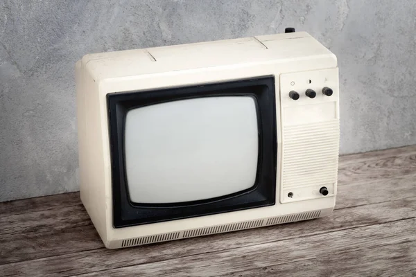 老式复古模拟小型电视机架在木制地板前灰色混凝土墙背景板上 — 图库照片