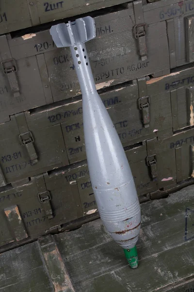 Soviet or russian 120 mm mortar shell on army green crate. Text in russian - type of ammunition, projectile caliber, projectile type, number of pieces and weight.