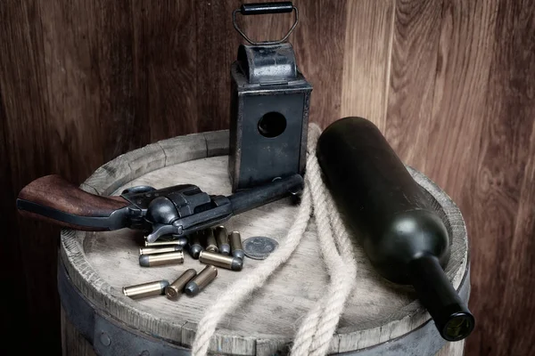 Old west revolver with cartridges and silver dollar and liquor bottle on wooden barrel