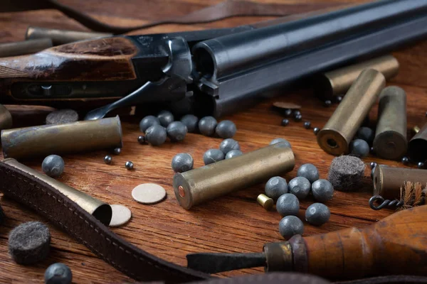 stock image Smooth-bored shotgun with brass cases and accessories for cartridge reloading on wooden table.