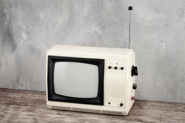 木制地板前灰色混凝土墙背景上的老式模拟小型电视机 — 图库照片