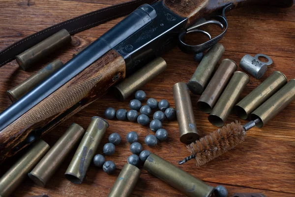 Hunting shotgun with brass cases and accessories for cartridge reloading on wooden table.