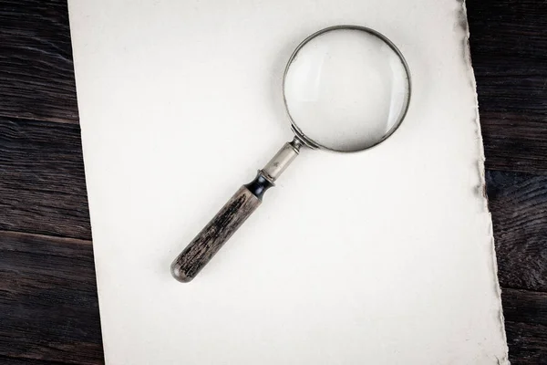 Antique vintage magnifying glass on paper background