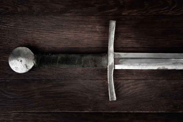 stock image Medieval vintage sword on wooden background.