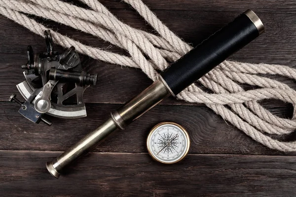 Retro vintage naval spyglass telescope with sextant and compass on wooden background