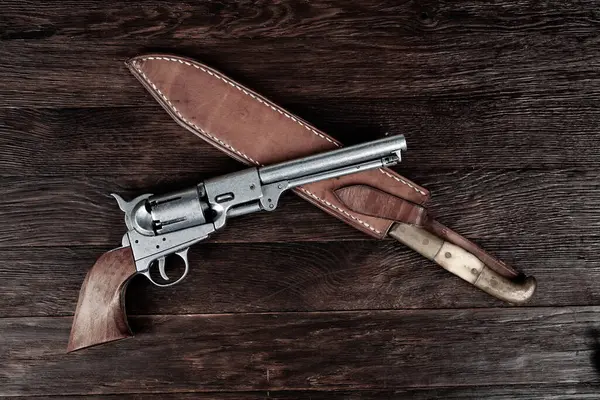 Old west weapon. Colt Revolver and knife with holster on wooden deck.