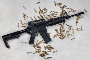 M4 carbine and 5.56mm shells and magazine with bullets on grey concrete surface background clipart