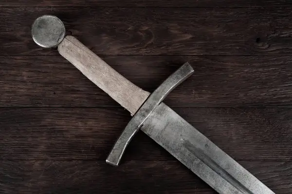 stock image Medieval vintage sword on wooden background.