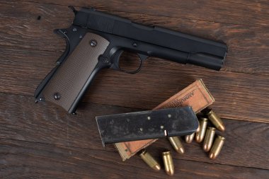 M1911 Automatic Pistol, Caliber .45 with magazine and ammunition on wooden background clipart