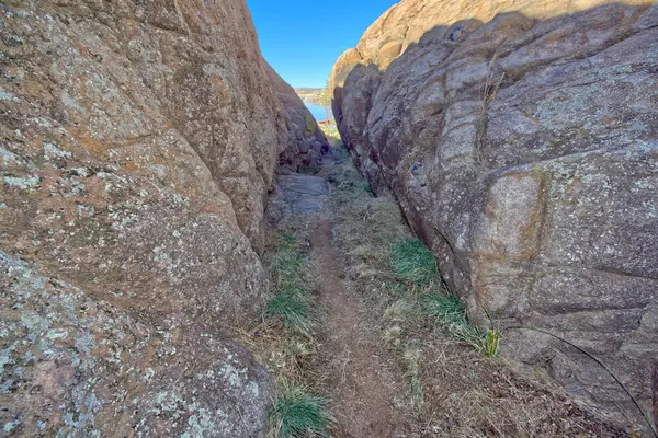 A narrow path between walls of Granite that marks the beginning of the Red Bridge Trail at Willow Lake in Prescott Arizona.