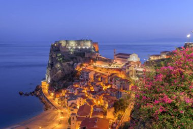 Scilla, Italy on the Mediterranean coast at twilight with seasonal flowers.