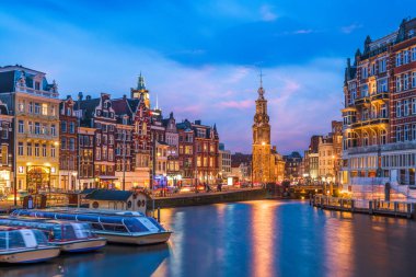 Amsterdam, Hollanda Kanalları üzerinde Munttoren Kulesi ile alacakaranlıkta şehir manzarası.