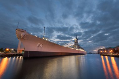 NORFOLK, VIRGINIA, ABD - 10 Mayıs 2023: USS Wisconsin (BB-64) deniz temalı Nauticus müzesinde akşam karanlığında yer almaktadır..