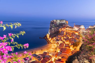 Scilla, Italy on the Mediterranean coast at twilight with seasonal flowers.